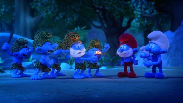 Bild 1 von 1: Begleitet von Handy und Baby übergibt Papa Schlumpf seinen Vorfahren aus der Steinzeit das Feuer.