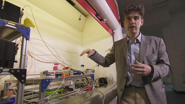 Bild 1 von 2: Biochemiker Lee Cronin von der University of Glasgow mit seiner selbstkreierten Maschine, die Millionen von Jahren chemische Evolution innerhalb weniger Wochen simuliert.