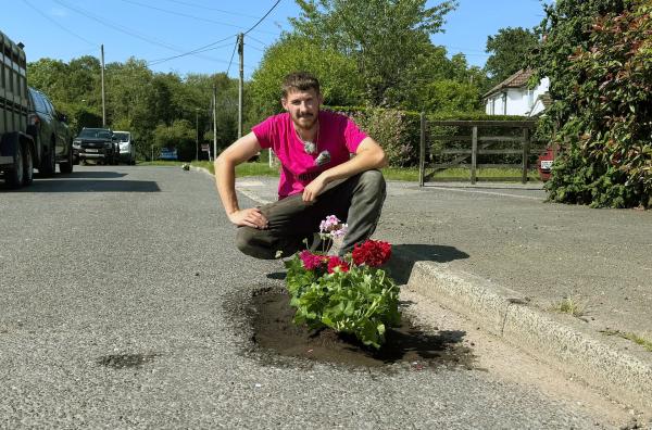 Bild 1 von 3: In der Grafschaft West Sussex gibt es kein ehrenamtliches Straßenwärter-Programm wie in Devon, Schlaglöcher aber zuhauf: Deswegen befüllt Handwerker Harry Smith-Haggett sie aus Protest mit Blumen.