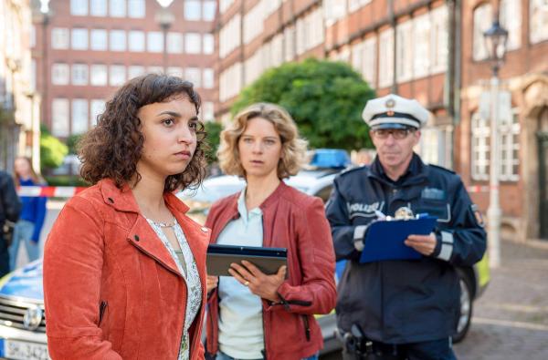 Bild 1 von 2: Im Bild: Aufgewühlt schildert Gesa Frahm (Genet Zegay, l.) Kommissarin Tomke Jennsen (Anjorka Strechel, M.) und einem Polizeibeamten (Komparse, r.) den Unfallhergang.