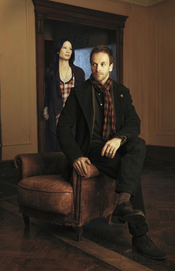 Bild 1 von 26: (1. Staffel) - Nachdem er in London in Ungnade gefallen ist und eine Zeit in einer Reha-Klinik verbrachte, muss Meisterdetektiv Sherlock Holmes (Jonny Lee Miller, vorne) ein neues Leben in Manhattan starten. Dort zwingt ihn sein wohlhabender Vater Seite an Seite mit Holmes schlimmsten Albtraum zu leben: der nüchternen \