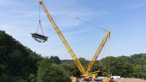 Bild 1 von 2: Nahe der schwäbischen Ortschaft Affalterbach hievt der Megakran eine Eisenbahnbrücke über einen Bach in einem Naturschutzgebiet.