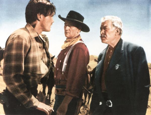 Bild 1 von 3: Medium shot of Jeffrey Hunter as Martin Pawley, John Wayne as Ethan Edwards, wearing a hat, and Ward Bond as Reverend Captain Samuel Johnson Clayton.