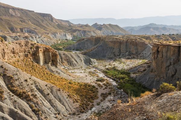 Bild 1 von 2: Dass Andalusien die trockenste Region Europas ist, ist an der Wüste von Tabernas sichtbar: Lavaklippen werfen kantige Schatten, hohe Dünen stehen als silbrig schimmernde Sandberge vor dem Horizont.