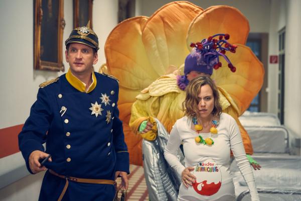 Bild 1 von 4: Lars (Sebastian Schwarz, l.) und Malte (Daniel Zillmann, 2.v.r.) begleiten Anita (Nadja Becker, r.), deren Wehen mitten im Karneval eingesetzt haben, ins Krankenhaus.