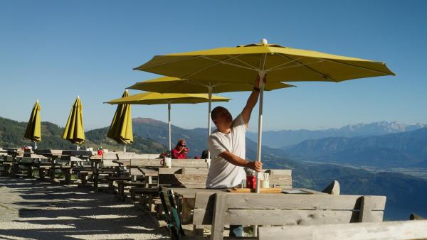 Bild 1 von 17: Im Bild: Gyaljen spannt die Sonnenschirme für die Gäste.