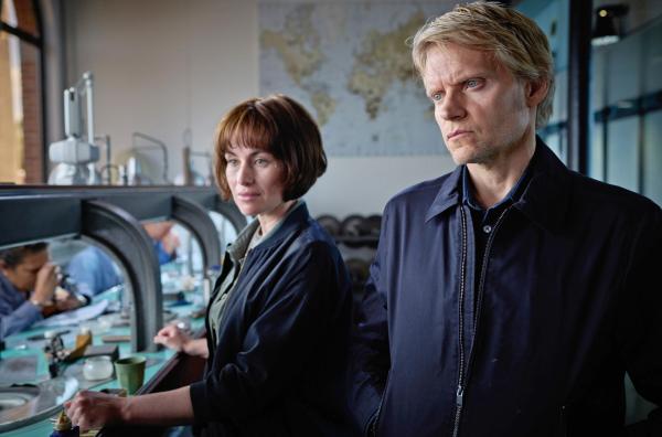 Bild 1 von 1: Lucienne (Maimie McCoy) und Van der Valk (Marc Warren) ermitteln im Diamanten-Unternehmen der Cuypers