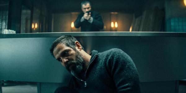 Bild 1 von 8: Im Bild: Reza (Yousef Sweid) versteckt sich vor dem Auftragskiller Brynner (Julian Sharp) hinter dem Vorbereitungstisch in der Bestattung.