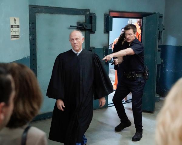 Bild 1 von 2: Der Richter Stevens (Jim Ortlieb, l.) wollte John Nolan (Nathan Fillion, r.) und weitere Besucher des Gerichts aus Platzgründen nicht in den Bunker lassen und hatte sie sogar mit einer Waffe bedroht, die ihm John abgenommen hat.