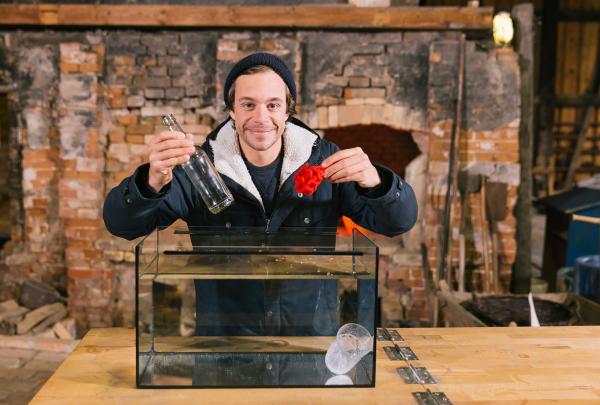 Bild 1 von 2: Tobi an seinem CheXperimentiertisch - mit dem roten Faden soll er die Glasflasche zerteilen. Knifflig!