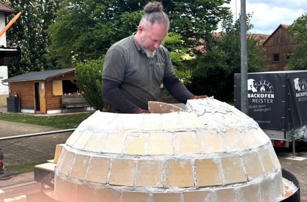 Bild 1 von 4: Ofenbauer Daniel Reisinger mauert die Kuppel des Pizzaofens. Der fertige Pizzaofen besteht aus 199 Steinen.