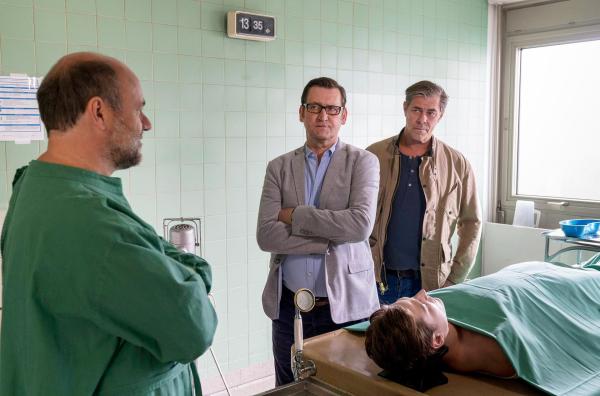 Bild 1 von 7: Im Bild: Der Pathologe Dr. Strahl (Christoph Tomanek, l.) berichtet Lars Englen (Ingo Naujoks, M.) und Finn Kiesewetter (Sven Martinek, r.) von seinen Obduktionsergebnissen zur Leiche von Alexander Blohm (Daniel Axt, liegend).