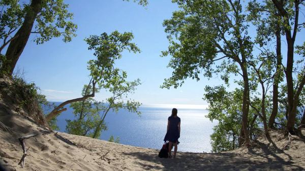 Bild 1 von 2: Ella Srocki mit Hund blickt vom Strand auf das Wasser.