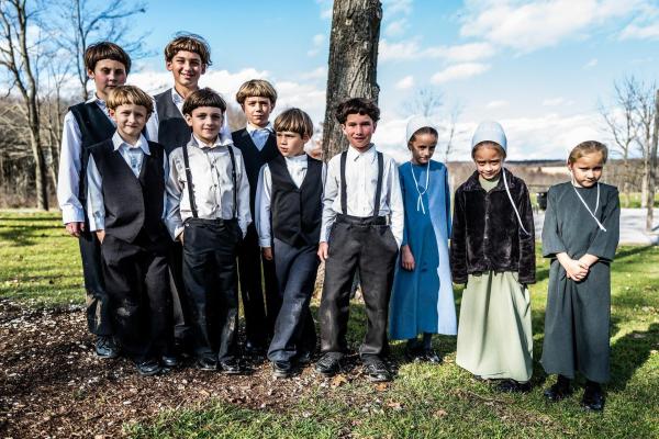 Bild 1 von 6: Im Bild: Eine Gruppe von Amish-Kindern stehen vor einem Baum.