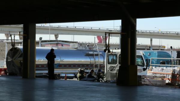 Bild 1 von 5: CBP officers and a cameraman are inspecting a shipping truck outside of a loading dock.