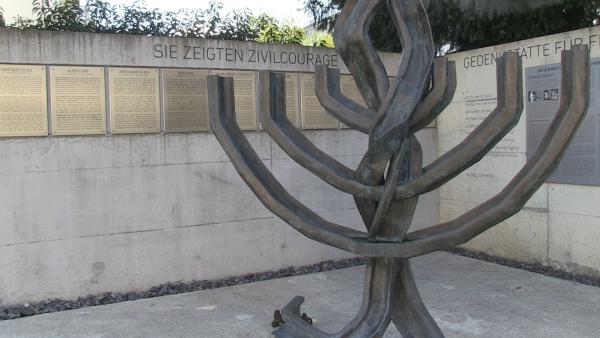 Bild 1 von 5: Eine Menora aus Eisenbahngleisen in Erinnerung an die Deportationszüge, im Hintergrund Tafeln zu Ehren von Judenrettern in der Schweiz.