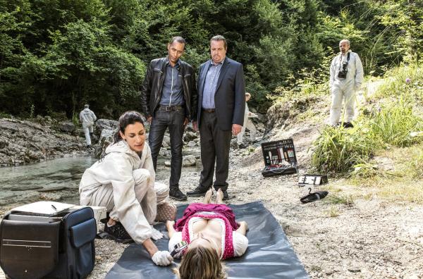 Bild 1 von 1: In der Ache wird eine junge Frau (Komparsin, liegend) tot aufgefunden. Sonja Bitterling (Genoveva Mayer, l.) untersucht die Leiche. Jerry Paulsen (Peter Marton, l.) und Benedikt Beissl (Andreas Giebel, r.) warten auf erste Hinweise wie die Frau ums Leben kam.