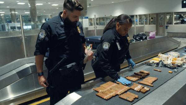 Bild 1 von 3: Officer Lefevre und seine Kollegin vom US-Grenzschutz am Internationalen Flughafen von Detroit Metro Airport stoppen einen Landsmann, der neben in den USA verbotenen kubanischen Zigarren auch THC-Gummibärchen im Koffer hatte.