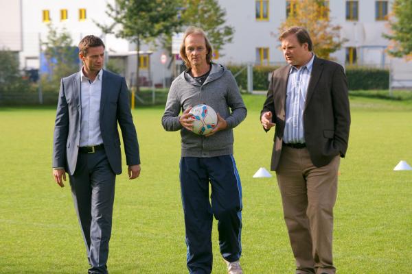 Bild 1 von 3: Mord auf dem Fußballplatz: Erste Ermittlungen führen Hansen (Igor Jeftic, l.) und Hartl (Michael A. Grimm, r.) zu Trainer Rainer Kosinsky (Eisi Gulp, M.).