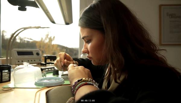 Bild 1 von 3: Mit ruhiger Hand und höchster Konzentration arbeitet eine angehende Uhrenmacherin an einem winzigen Uhrwerk.