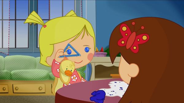 Bild 1 von 6: Zoé sticht mit einem dreieckigen Ausstechförmchen Plätzchen aus, Lili schaut erstaunt zu.