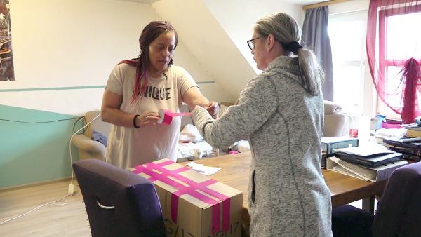 Bild 1 von 3: Jannie (li.) will wichtige Dokumente mit der Post in die USA vorausschicken. Unterstützung erhält sie von ihrer Freundin Sandra (re.)