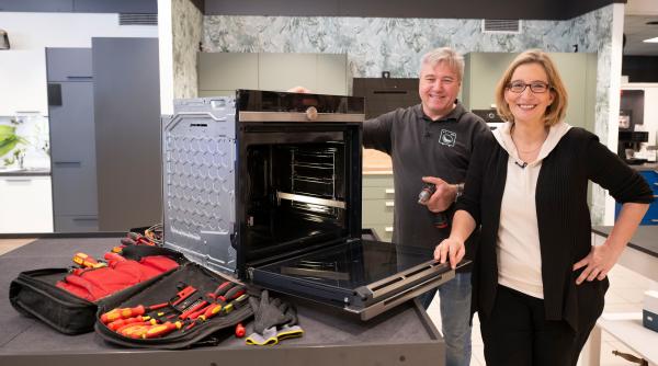 Bild 1 von 2: Experte Jürgen Winter (l) zeigt Hauswirtschaftsmeisterin Yvonne Willicks, was man am Backofen alles selbst reparieren kann und was besser der Fachmann übernehmen sollte.
