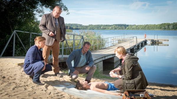 Bild 1 von 9: Max (Ole Heinzelmann, 2.v.r.) ist ertrunken, aber eindeutige Hinweise kann die Pathologin Helene Sturbeck (Katharina Blaschke, r.) noch nicht geben. Jedoch war Max ein guter Schwimmer. Anzeichen auf äußere Gewalt gibt es nicht. Die Kommissare Börensen (Claudia Schmutzler, l.), Reuter (Udo Kroschwald, 2.v.l.) und Pöhlmann (Dominic Boeer, M.) tappen im Dunkeln. Warum ist Max nochmal zum See zurückgekommen? Und was ist dort mit ihm passiert?