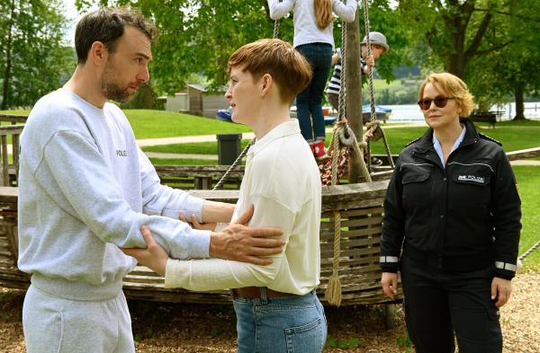 Bild 1 von 1: Im Bild: Frederik (Beniamino Brogi, l.) kann seiner Schwester Lea Louise Danner (Eva-Maria Jost, M.) kaum in die Augen schauen, als er ihr die traurige Nachricht auf einem Spielplatz mit ihren beiden Kindern überbringt. Lea-Louises Mann war bei einer gemeinsamen Bootstour mit Frederik, überfallen und getötet worden (mit Floriane Daniel, r.).
