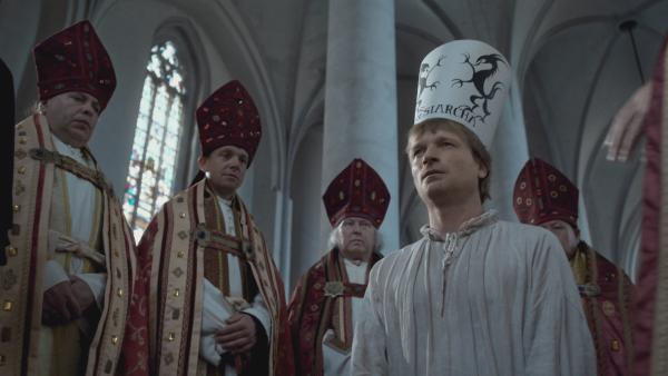 Bild 1 von 3: Nach der Verurteilung zum Ketzer wird Jan Hus eine Papierkrone aufgesetzt, auf der drei Teufel gemalt sind. Ein Symbol dafür, dass seine Seele dem Teufel übergeben wird.