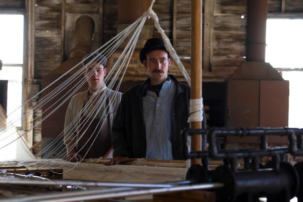 Bild 1 von 11: Spielszene: Gustav Weißkopf (Darsteller unbekannt) beäugt kritisch seine Flugmaschine Nr. 21.