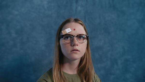 Bild 1 von 5: Floor (Bobbi Mulder) posiert für das Schulfoto, als ihr Pflaster genau vor der Aufnahme abgeht.