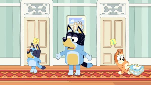 Bild 1 von 3: Dad wird in ein Hotel-Spiel verwickelt, in dem Bluey und Bingo ein verrücktes Hotel leiten und Dad der umsorgte Gast ist. Doch als Bluey das Spiel zu sehr an sich reißt, will Bingo nicht mehr mitspielen. Bluey muss lernen, Kompromisse zu schließen, damit das Spiel weitergehen kann.