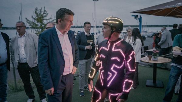 Bild 1 von 1: Ministerpräsident Sven Schulze unterhält sich bei einem Parteifest mit einem Akrobaten, der für Stimmung sorgt.