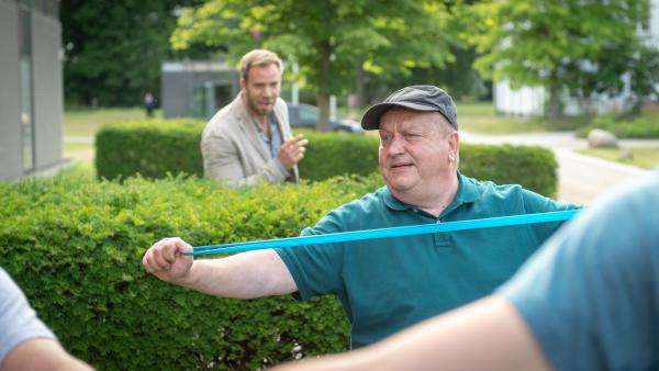 Bild 1 von 7: Lars Pöhlmann (Dominic Boeer, l.) mahnt seinen Chef, denn trotz verordnetem Kuraufenthalt kann Reuter (Udo Kroschwald, r.) das Arbeiten nicht lassen. Er hat ermittelt, dass der Tote im Moorbad einen Kurschatten gehabt hat. Dabei ist der Mann verheiratet. Seine Frau hat ihn bisher in der Klinik nicht besucht. Reuter hängt sich inkognito in den Fall. Kann er den Fall von der Klinik aus lösen?