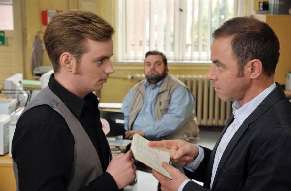 Bild 1 von 1: Jonas Wolter (Jan Niklas Berg, links) und Hauptkommissar Kleinert (Felix Eitner, rechts) diskutieren im Beisein von Ollie (Christoph Hagen Dittmann, Mitte) die Bankdaten des Yogastudios.