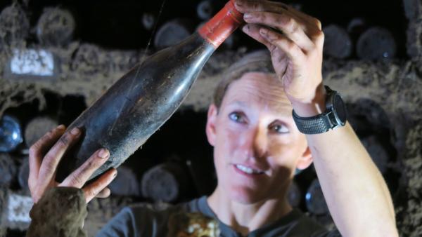 Bild 1 von 3: Winzerin Theresa Breuer kontrolliert im Weinkeller ihres Familienbetriebs in Rüdesheim eine gereifte Flasche - zwischen jahrhundertealter Weintradition und den Herausforderungen des Klimawandels.