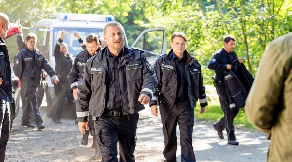 Bild 1 von 1: Im Bild: Der Leiter der Suchstaffel Horst Felder (Matthias Komm, M.), kommt in Begleitung von Bastian (Paul Lux, 3.v.r.) und seiner Truppe am Tatort an.