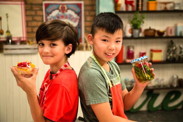 Bild 1 von 7: Mini-Paprika eingelegt oder nur mit Frischkäse? Ben und Felix zeigen, wie es geht. Ben mit einer Schale Mini-Paprikas, gefüllt mit Frischkäse. Felix hält ein Glas mit eingelegten Mini-Paprikas.