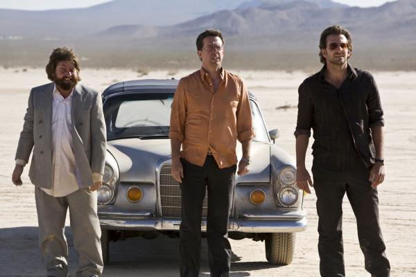 Bild 1 von 6: Zach Galifianakis as Alan, Ed Helms as Stu, and Bradley Cooper as Phil standing in desert with car in background.
