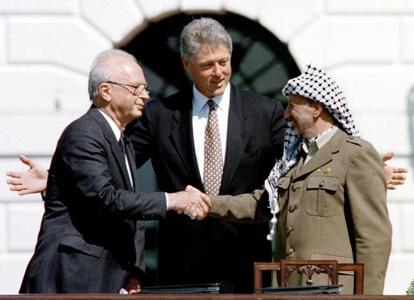 Bild 1 von 4: Unter der Vermittlung von US-Präsident Bill Clinton (M.) reichen sich der israelische Ministerpräsident Yitzhak Rabin (l.) und PLO Chef Yasir Arafat (r.) am 13. September 1993 die Hand. Die Unterzeichnung des Oslo-Abkommens ist ein Zeichen der Hoffnung für Frieden im Nahen Osten.