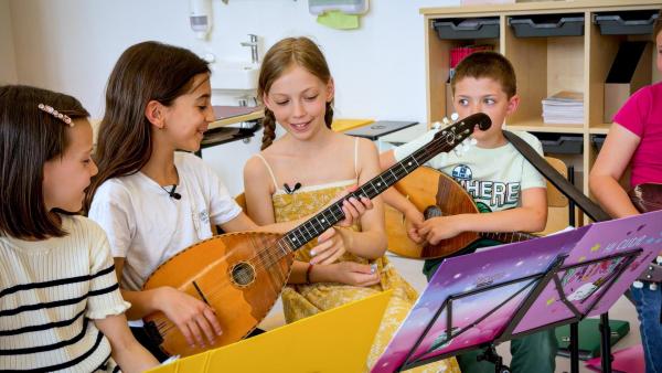 Bild 1 von 3: Im Bild: Lara bekommt Unterricht beim Spielen der Tamburizza.