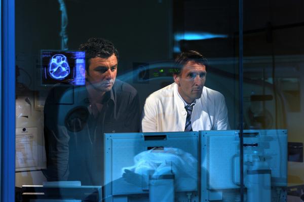 Bild 1 von 1: Bergdoktor Martin (Hans Sigl, l.) und Chefarzt Dr. Kahnweiler (Mark Keller, r.) studieren auf dem Monitor die Scans von Andreas Schädel.
