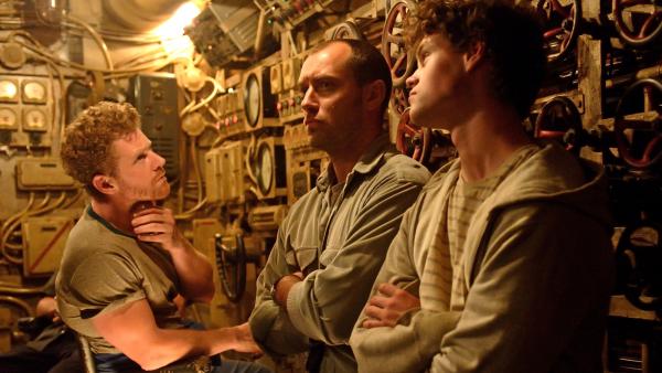 Bild 1 von 2: Gittens (Branwell Donaghey, li.) Captain Robinson (Jude Law) und Tobin (Bobby Schofield, re.)