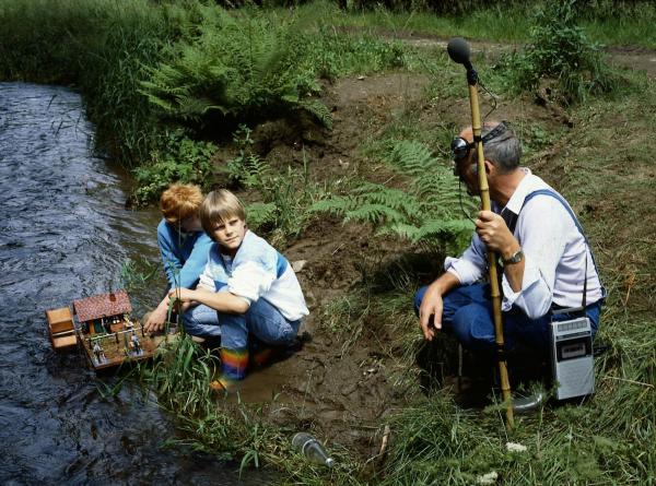 Bild 1 von 3: Peter (Peter Lustig, r.) fragt die beiden Jungs, ob man an dieser Stelle gut das Plätschern des Baches aufzeichnen kann. Er ist auf der Suche nach einer geeigneten Stelle für seine Bach-Komposition.