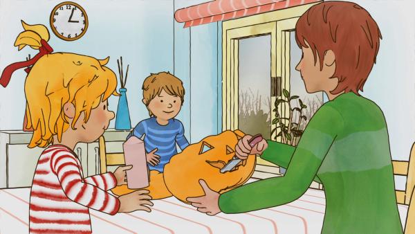 Bild 1 von 4: Mama bastelt mit Conni und Jakob einen Halloween-Kürbis.