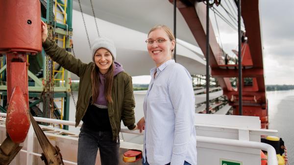 Bild 1 von 5: Checkerin Marina (links) auf einem Frachtschiff im Nord-Ostsee-Kanal, das Rotorblätter für Windräder geladen hat.