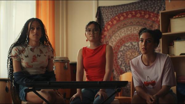 Bild 1 von 3: Châu (Ngoc Nhi Ha Tran, Mitte) hat einen fragwürdigen Plan, wie sie endlich die Melodie für das Bandstück perfekt vorführen kann. Dafür braucht sie die Hilfe der beiden älteren Schulkameradinnen Julia (Claire Nae Lienshöft, links) und Alina (Imane Lahna, rechts) aus der Musik-AG.