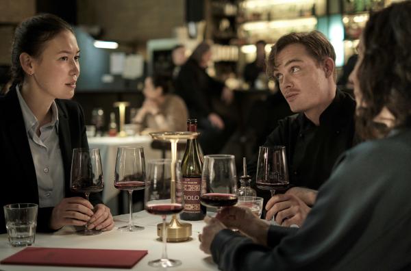 Bild 1 von 8: Henry Mahn (Malaya Stern Takeda, li.) und Anna Conti (Désirée Nosbusch, re.) werden von dem Restaurantbesitzer Milan Serra (David Schütter, Mi.) auf einen Wein eingeladen.