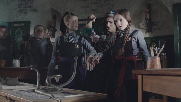 Bild 1 von 7: Mildreds (Bella Ramsey, r.) Gefäß aus Ton hat sich in Schlangen verwandelt. Ob Esther (Jenny Richardson, l.) etwas mit diesem unschönen Zauber zu tun hat? So wird sich die Freundschaftsfalle zwischen den beiden nicht auflösen. Die neue Kunstlehrerin Frau Schimmel (Mina Anwar) stoppt den Schlangen-Zauber.